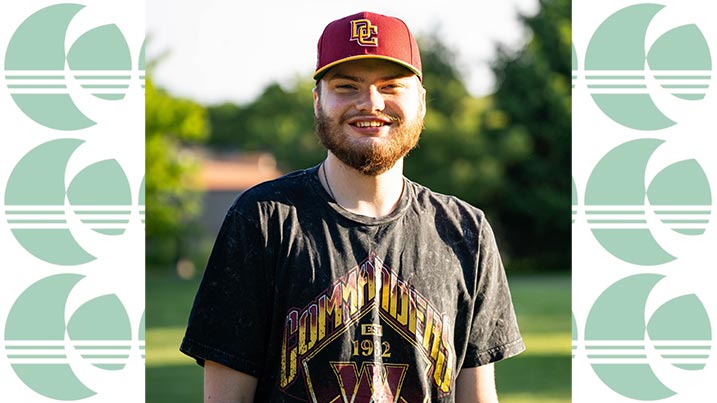 The image is of Zach Osborne standing outside in a sunlit area with greenery in the background. The individual is wearing a maroon baseball cap with a yellow logo and a black T-shirt featuring colorful graphics. The cap has a bold yellow emblem, and the T-shirt design includes the word "COMMANDERS" in yellow above a large "W" in red, outlined with yellow. Below the letter, text and smaller stars are visible.